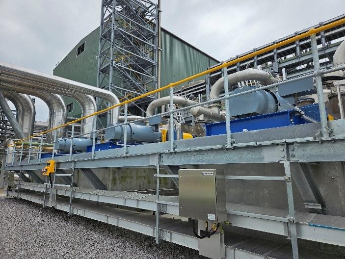 Vacuum-pump | JeotermalHaberler - Jeotermal Haber Industrial piping system on a metal walkway with yellow railings, large ducts and machinery against a green warehouse backdrop.